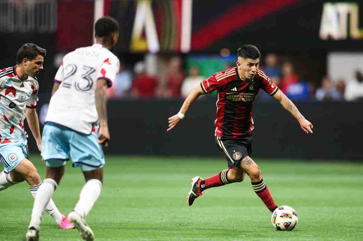 Three soccer players during a soccer game, two from the Chicago Fire trying to take the ball from Thiago Almada from Atlanta United.