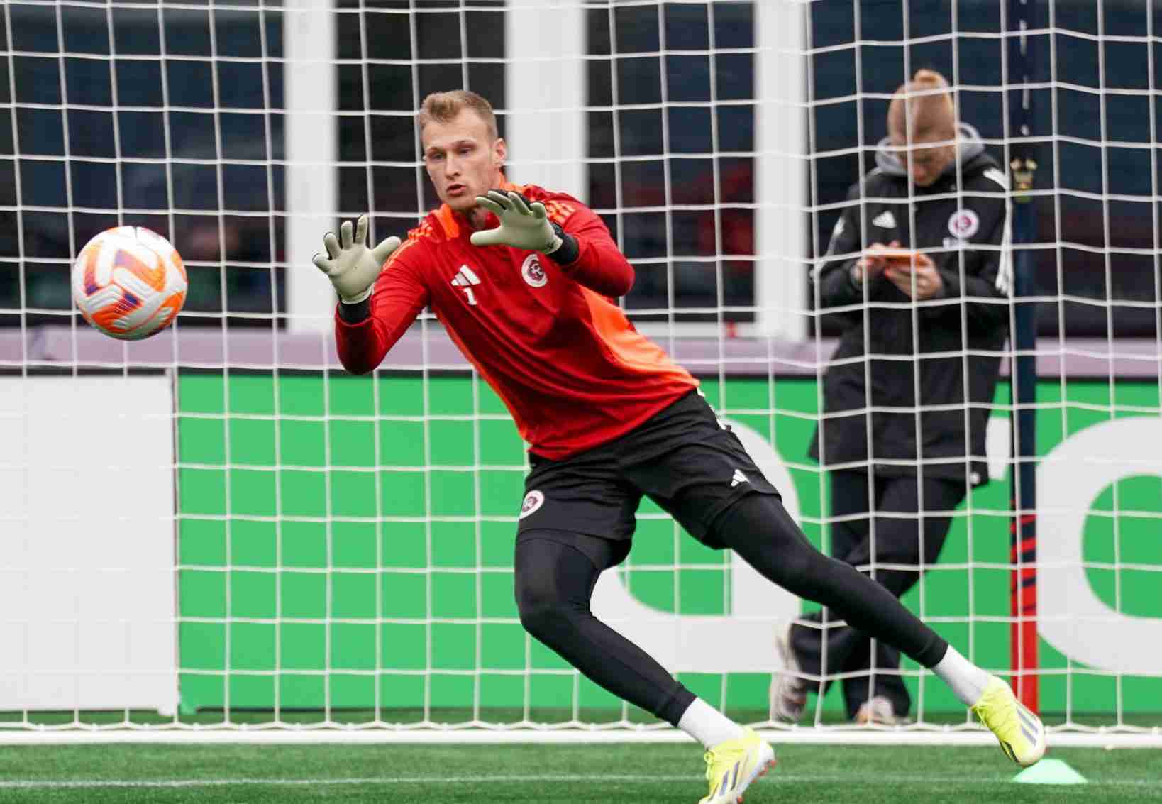 A goalie jumps to catch a ball during practice