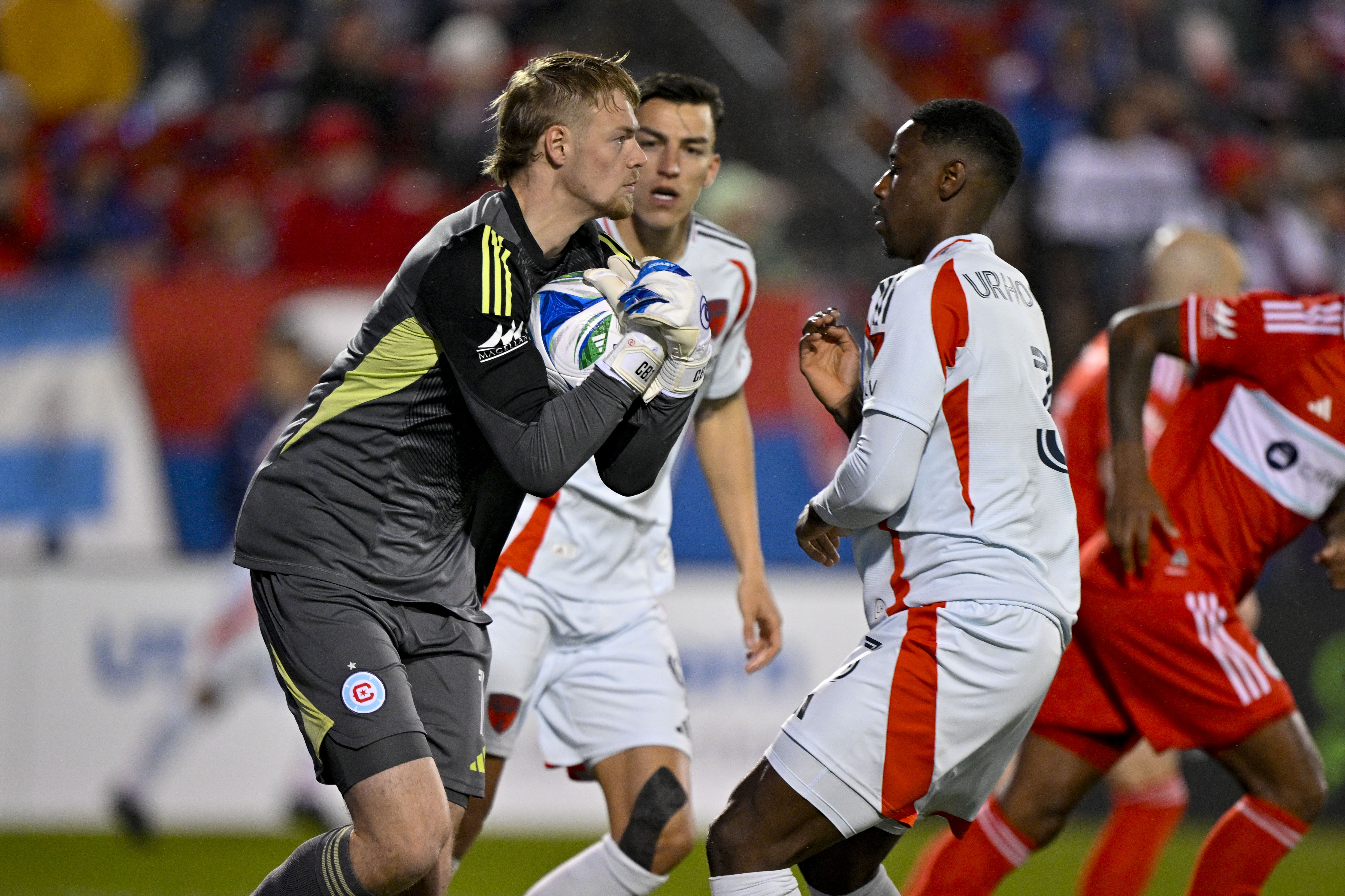Mar 8, 2025; Frisco, Texas, USA; Chicago Fire goalkeeper Chris Brady (1) controls the ball in front of FC Dallas defender Osaze Urhoghide (3) during the first half at Toyota Stadium.