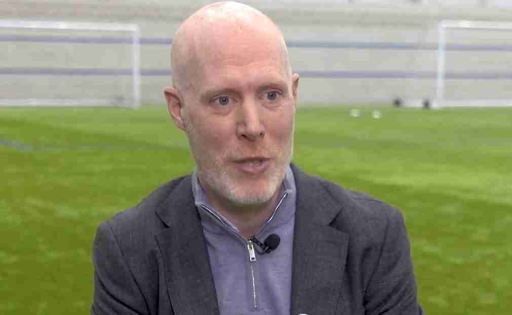 Close in shot of Gregg Blackburn, wearing a jacket and blue shirt on a training pitch.