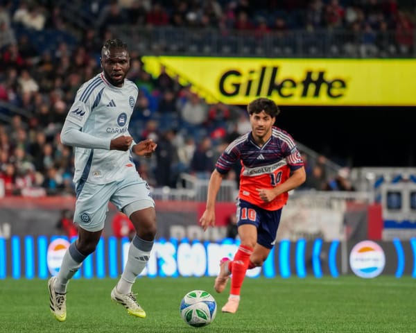 Rominigue Kouamé plays the ball forward against Carles Gil during the Chicago Fire's game against the New England Revolution